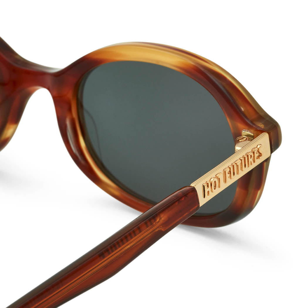 close up side angle shot of the caramel tortoiseshell sunglasses with the gold Hot Futures text branding on the arms shown