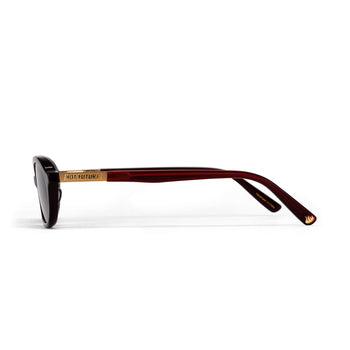 Sunglasses with a gold frame and cherry red arms on a white background