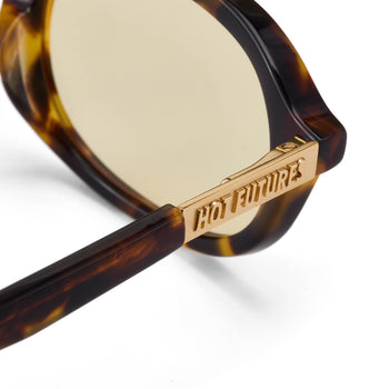 Sunglasses with tortoiseshell frame and gold arm featuring 'Hot Future' branding on a white background.
