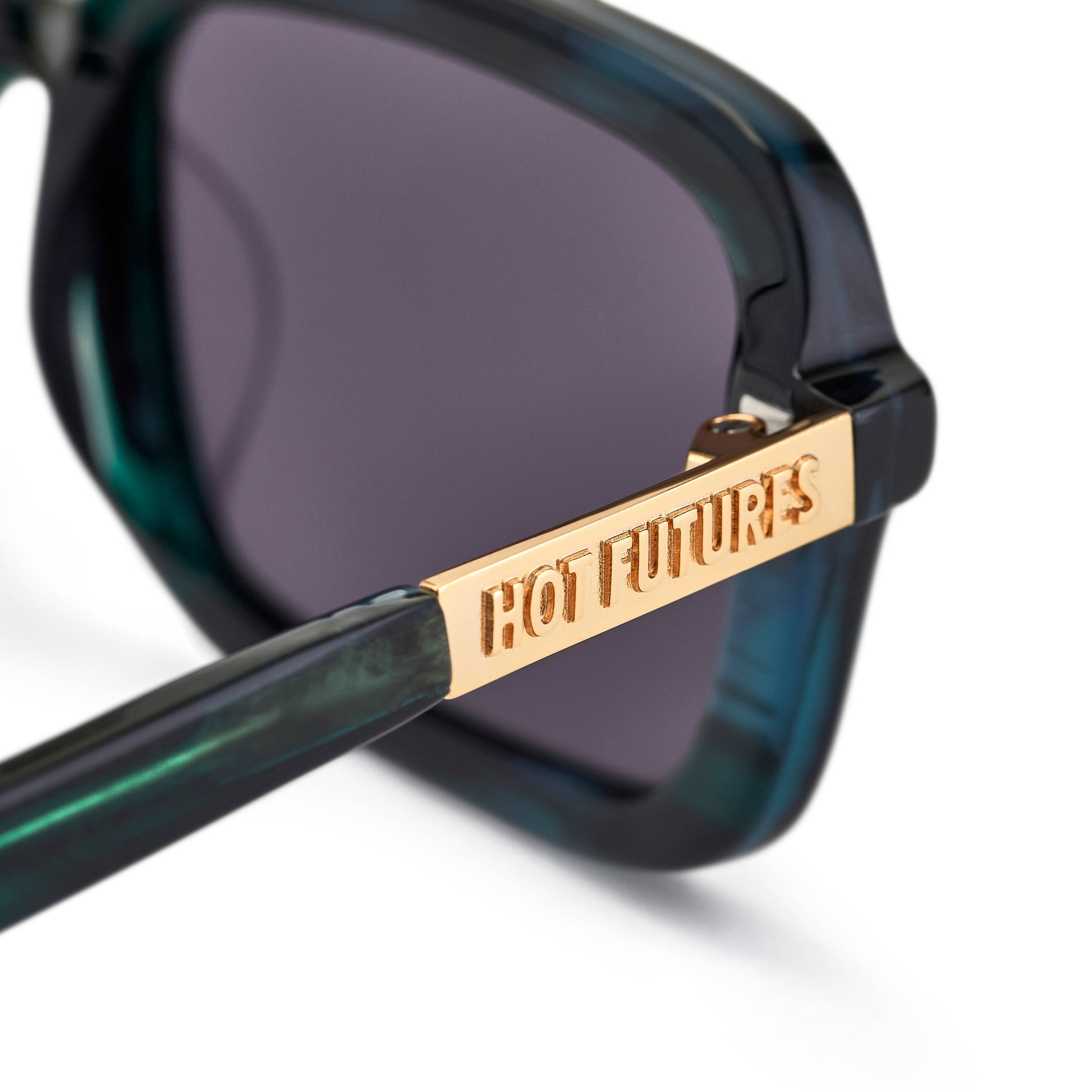 A pair of eco green crystal smoke tinted rectangular sunglasses shot close up showing the gold branding and darkness of the lenses