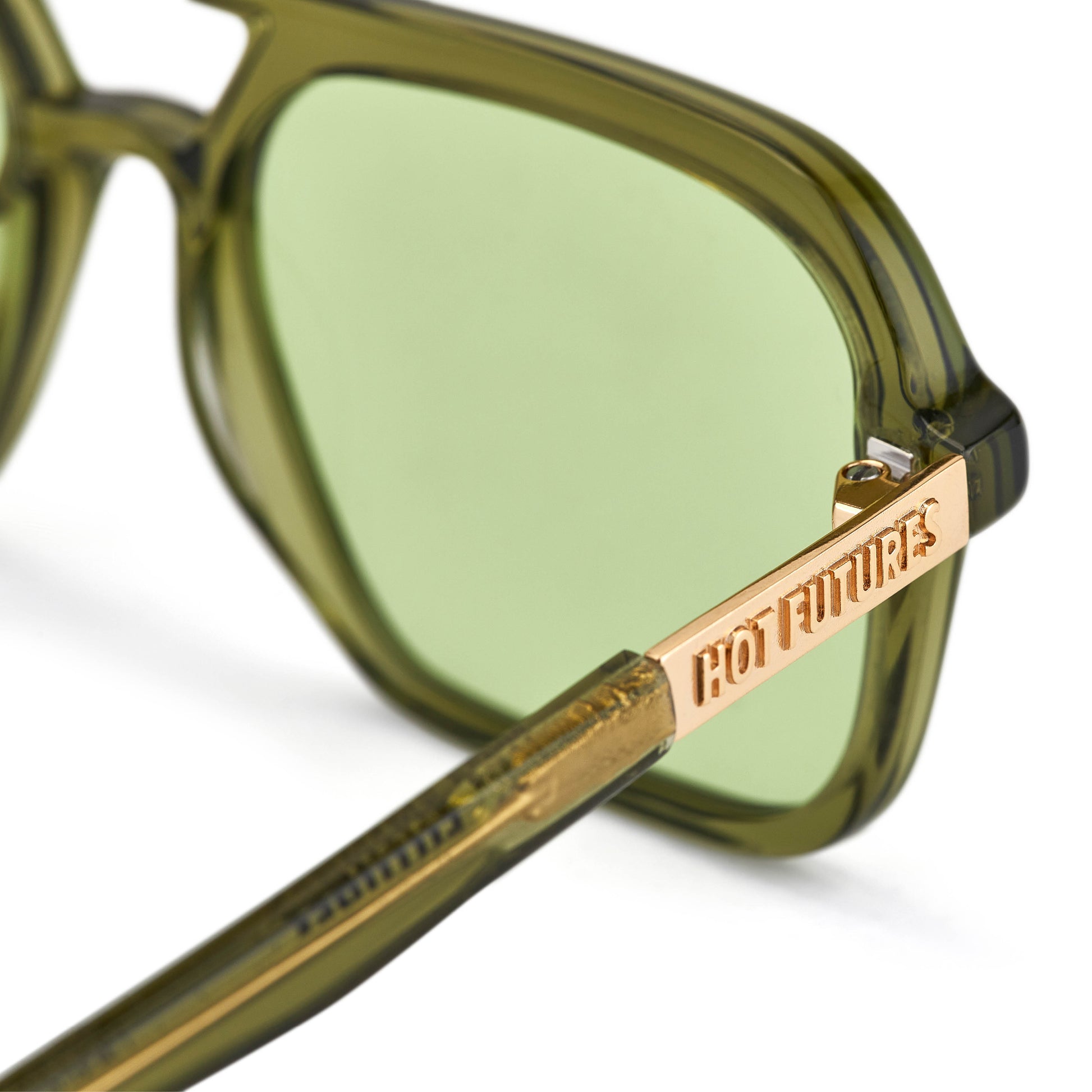 A pair of green tinted aviator sunglasses with an olive green frame. With gold Hot Futures text branding on sides of glasses arms