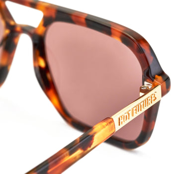 A pair of tortoiseshell patterned sunglasses with a slim rectangular aviator frame 
