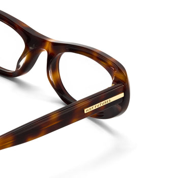 Close-up of tortoiseshell glasses with 'HOT FUTURES' label on a white background