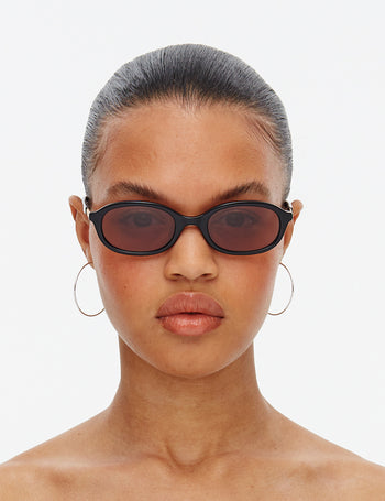 Model wearing black sunglasses with a plain background