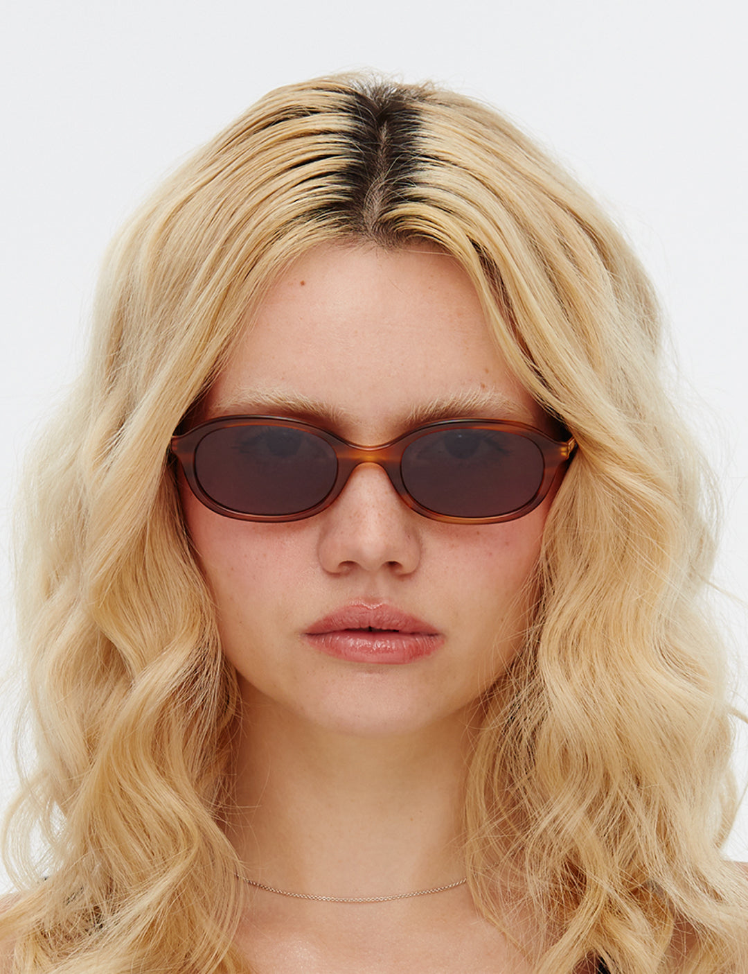 A pair of oval-shaped sunglasses with a caramel tortoiseshell acetate frame and dark green lenses.