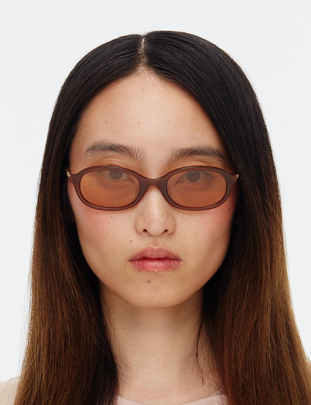 A pair of brown elliptical sunglasses with gold tinted lenses and integrated alloy hinges.