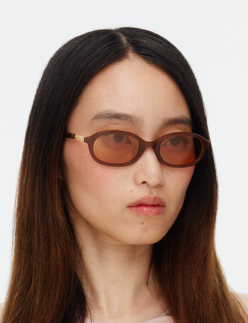 Person wearing brown sunglasses with a plain background