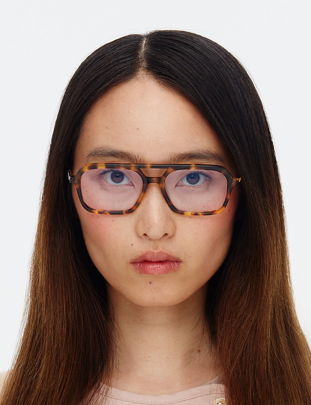 Person wearing tortoiseshell glasses with a plain background