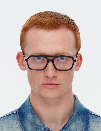 Man wearing black glasses and a denim shirt on a white background