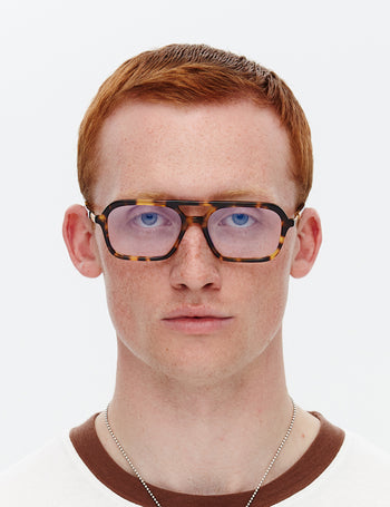 Person wearing tortoiseshell glasses on a white background