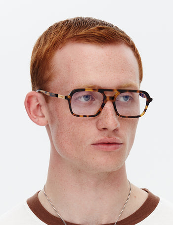 Person wearing tortoiseshell glasses on a white background