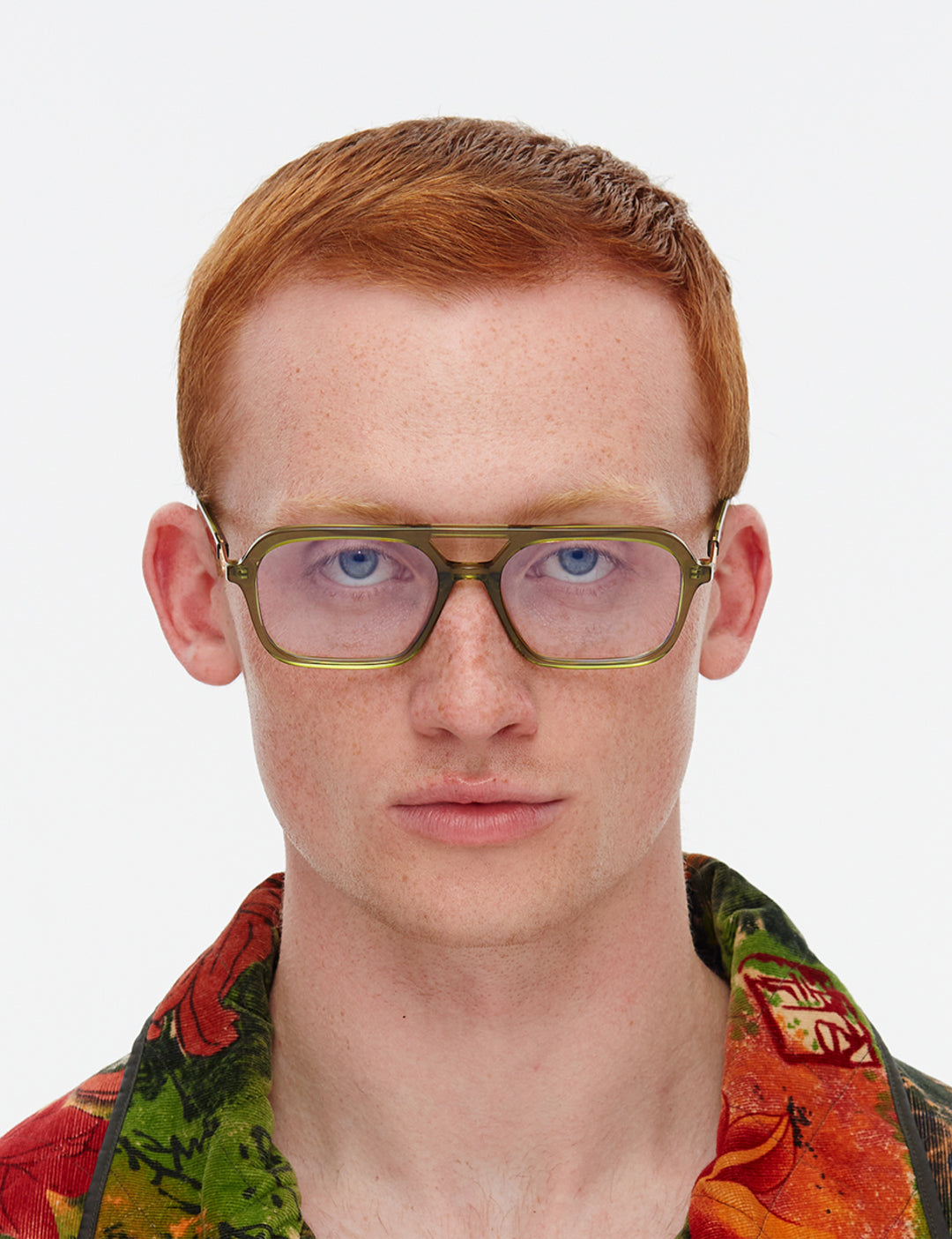Person wearing glasses with a colourful shirt on a white background