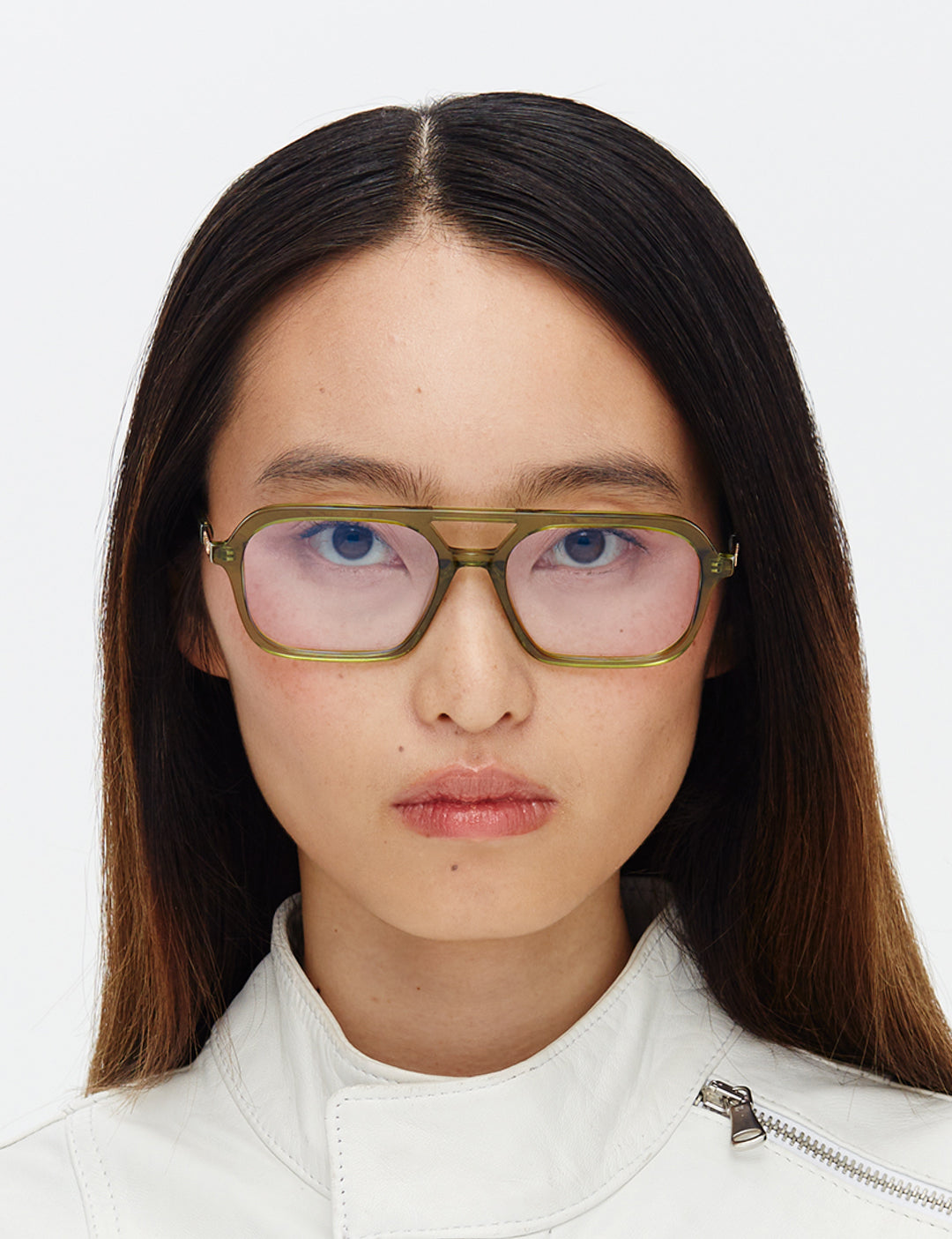 Person wearing green-framed glasses with a plain white background