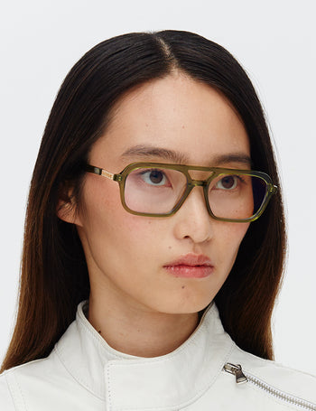 Person wearing green glasses with a plain white background