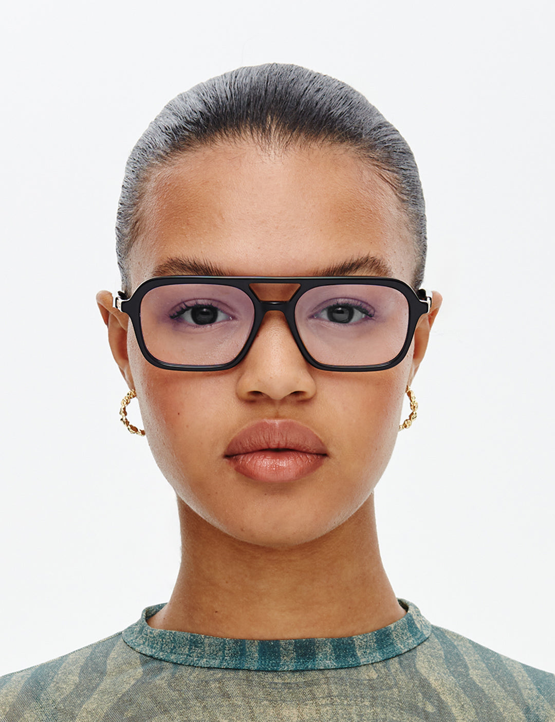 Person wearing large black-framed glasses on a plain background