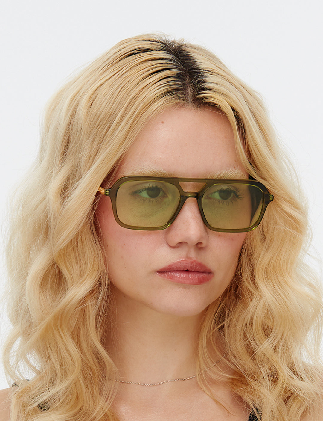 Person with blonde hair wearing the Green Dime sunglasses by Hot Futures against a white background