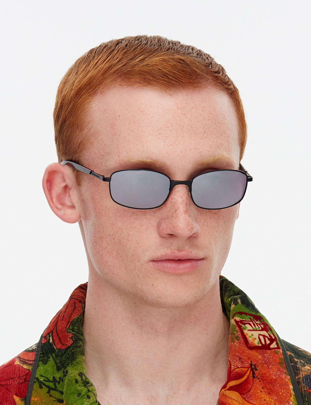Person wearing sunglasses with a colorful shirt on a white background