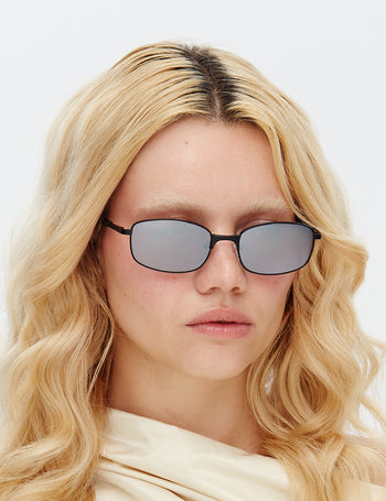 Model wearing Hot Futures Black Mirror lens sunglasses with a plain background