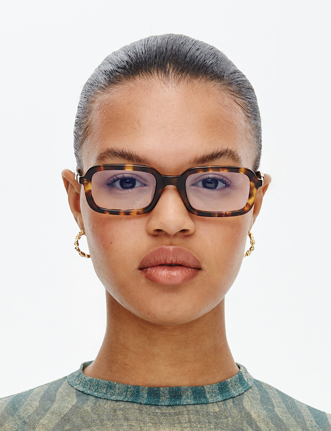 Person wearing tortoiseshell glasses with a neutral background