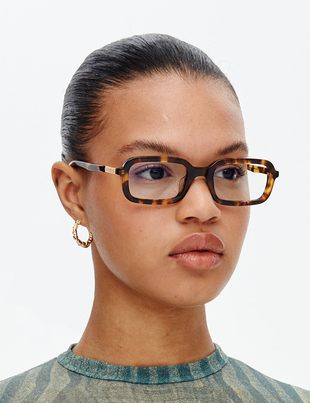 Person wearing tortoiseshell glasses with a neutral background
