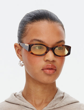 Model wearing tortoiseshell sunglasses with a neutral background