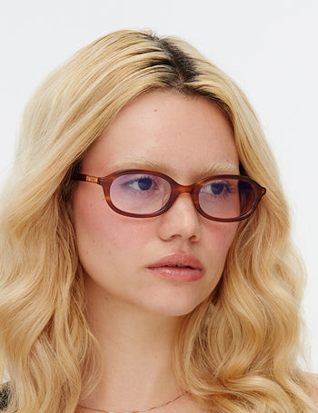 Person with blonde hair and glasses on a plain background