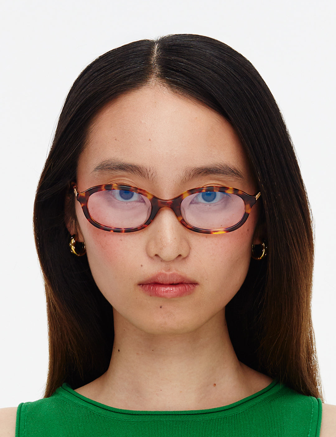 Person wearing tortoiseshell glasses with a plain background