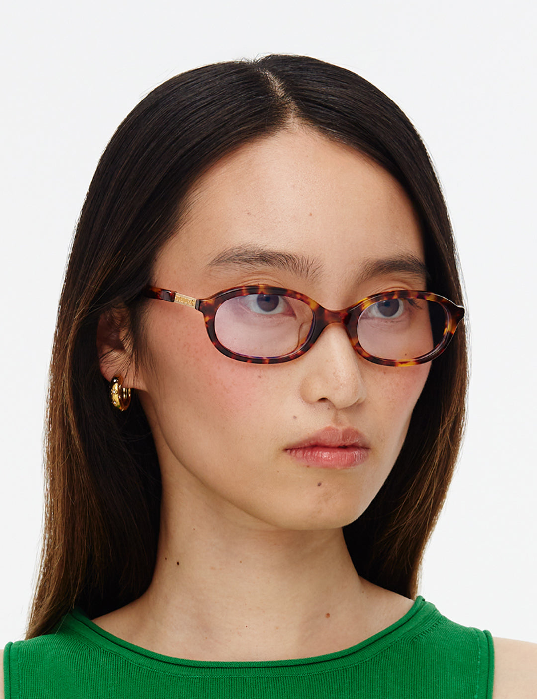 Person wearing tortoiseshell glasses with a plain background