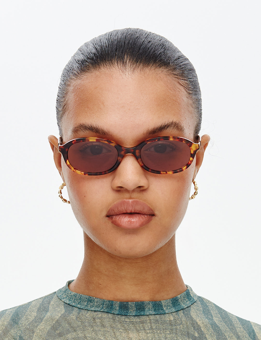 Woman wearing tortoiseshell sunglasses with a neutral background